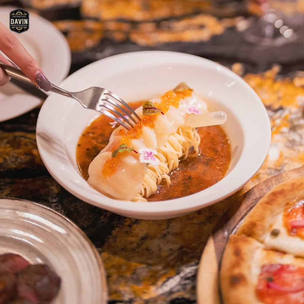 Close-up of a creative seafood dish (scallops and noodles with caviar and sauce) demonstrating the high-end menu quality of the Davin Cafe banquet restaurant.