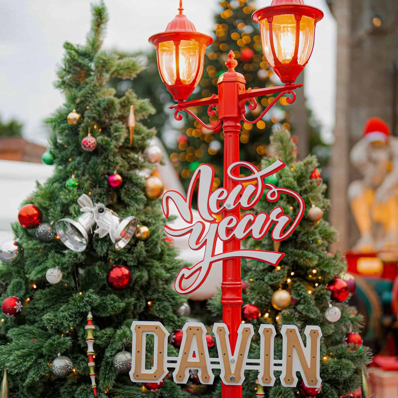 A close-up of a festive red lamp post decorated with a bold "New Year" sign and colorful Christmas ornaments at Davin Cafe.
