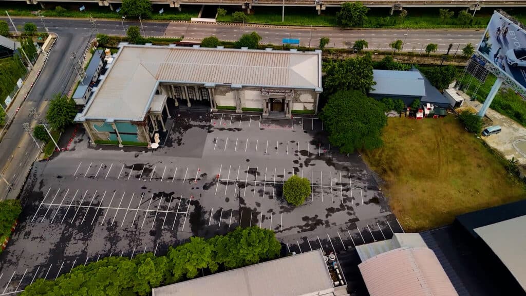 ภาพถ่ายมุมสูงจากโดรนของ Davin Cafe สถานที่จัดงาน แสดงสถาปัตยกรรมคลาสสิกและลานจอดรถขนาดใหญ่ที่รองรับรถได้กว่า 250 คัน ใกล้ทางด่วนรามอินทรา.