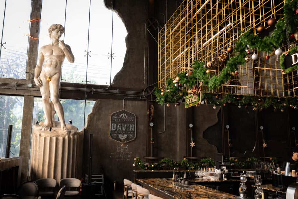 An artistic interior event venue decorated for Christmas 2025, blending classical sculpture, industrial design, and festive Christmas décor, ideal for Christmas parties, year-end celebrations, and premium holiday events