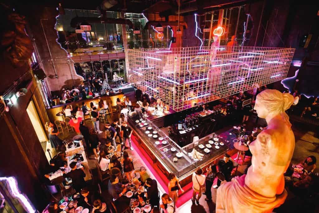 มุมมองจากด้านบนของสถานที่จัดปีใหม่ในบรรยากาศอินดัสเทรียลลอฟต์ มีผู้ร่วมงานจำนวนมาก อาหาร เครื่องดื่ม และพื้นที่จัดกิจกรรมที่รองรับงานเลี้ยงส่งท้ายปีทั้งแบบสังสรรค์และอีเวนต์องค์กรอย่างมีระดับ