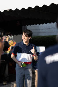 ชายหนุ่มยิ้มแย้มในงานอีเวนต์ที่ Davin Cafe พร้อมของขวัญและบรรยากาศสนุกสนาน.