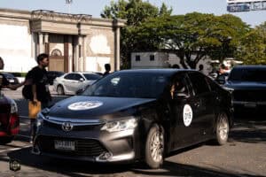 รถแท็กซี่สีดำจอดอยู่ในลานจอดรถหน้าสถานที่จัดงาน Event Gallery: The First Ultimate เที่ยวสุดโลก | 15.