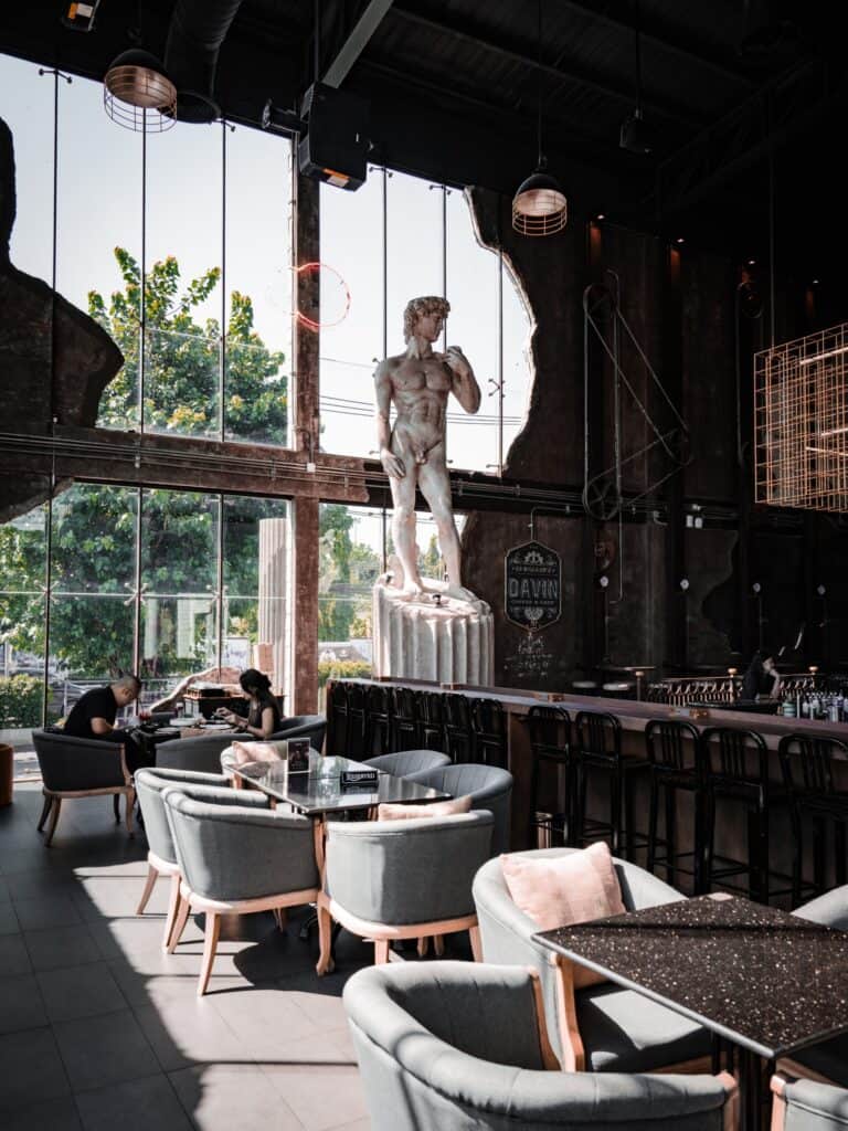 Interior view of Davin Cafe in Bangkok featuring a striking European-industrial design with a large David sculpture, spacious seating, and a relaxed atmosphere ideal for specialty coffee, meetings, and casual work sessions.