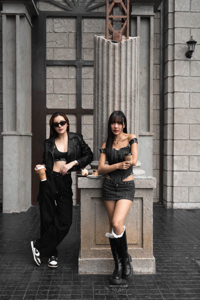 Two customers posing with drinks in front of a Roman-style column at Davin Cafe, a distinctive photo spot favored by fashion-focused visitors looking for a unique and visually striking café experience