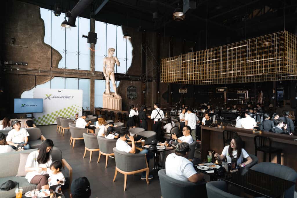 A lively indoor scene at Davin Cafe during the Songkran period, with guests enjoying seating areas and the coffee bar, creating a relaxed and comfortable escape from Bangkok’s festive heat