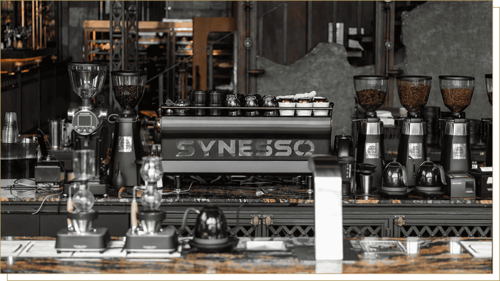 Professional specialty coffee station at Davin Cafe featuring a Synesso espresso machine and industrial grinders, perfect for high-quality coffee catering and artisan brew experiences.