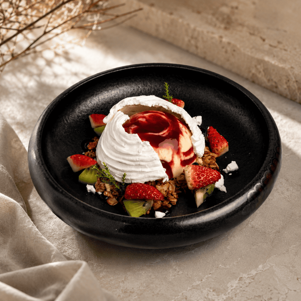 พาฟโลวาของ Davin Cafe เสิร์ฟในชามสีดำพร้อมเมอแรงก์กรอบ ครีมซอสเบอร์รี สตรอว์เบอร์รี กีวี และกราโนล่า เป็นเมนูของหวานที่เหมาะกับบทความร้านเค้ก เลียบด่วนสำหรับคนที่มองหาขนมหวานรสสดชื่น จัดจานสวย และเข้ากับบรรยากาศคาเฟ่พรีเมียม